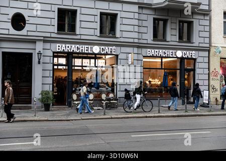 Berlin, Berlin, Deutschland. Oktober 2025. Am 25. Oktober 2025 laufen und radeln die Menschen am Barachel Café in Berlin vorbei. Die helle Fassade des Cafés und die Sitzplätze im Freien ziehen sowohl Einheimische als auch Besucher an. (Kreditbild: © Michael Kuenne/PRESSCOV via ZUMA Press Wire) NUR REDAKTIONELLE VERWENDUNG! Nicht für kommerzielle ZWECKE! Stockfoto