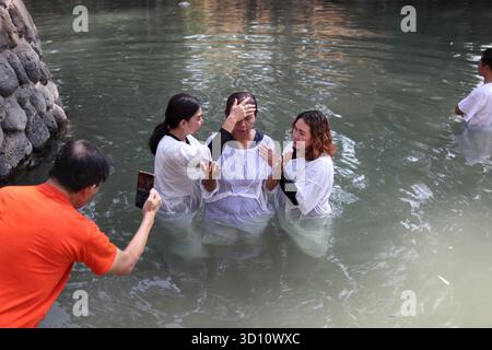 Yardenit Taufstätte, protestantische indonesische Frau trägt ein weißes Kleid, betet und gehalten von einem sie Pastor (L), um im Jordan von 2 Frauen getauft zu werden Stockfoto