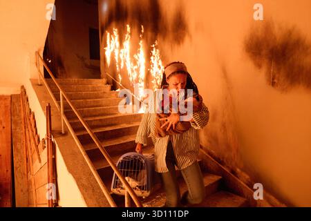 Frau entkommt Feuer mit Baby und Haustier, läuft Treppen in rauchgefüllten Gebäude hinunter, Notevakuierung, Rettung aus brennendem Gebäude, dramatisch Stockfoto