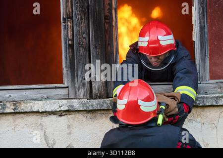 Feuerwehrmann, der ein Baby aus dem brennenden Gebäude rettet, Feuerwehrmann in Aktion Kind retten, Notfallsituation, Feuer im Haus, Gefahr, Rettungsaktion Stockfoto