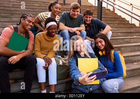 Verschiedene Studentengruppen machen Selfie auf der Uni-Treppe Stockfoto