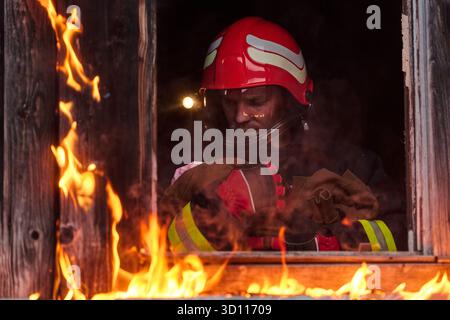 Feuerwehrmann, der ein Baby aus dem brennenden Gebäude rettet, Feuerwehrmann in Aktion Kind retten, Notfallsituation, Feuer im Haus, Gefahr, Rettungsaktion Stockfoto