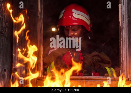 Feuerwehrmann, der ein Baby aus dem brennenden Gebäude rettet, Feuerwehrmann in Aktion Kind retten, Notfallsituation, Feuer im Haus, Gefahr, Rettungsaktion Stockfoto