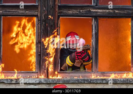 Feuerwehrmann, der ein Baby aus dem brennenden Gebäude rettet, Feuerwehrmann in Aktion Kind retten, Notfallsituation, Feuer im Haus, Gefahr, Rettungsaktion Stockfoto