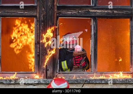 Feuerwehrmann, der ein Baby aus dem brennenden Gebäude rettet, Feuerwehrmann in Aktion Kind retten, Notfallsituation, Feuer im Haus, Gefahr, Rettungsaktion Stockfoto