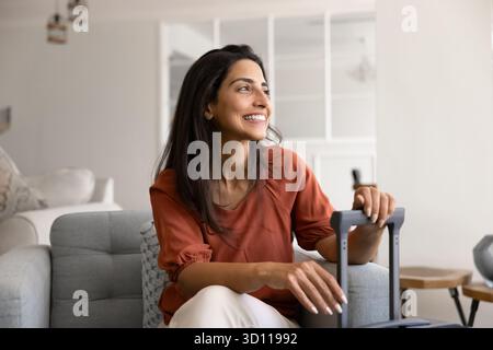 Glückliche junge lateinische Touristenfrau, die im Hotelzimmer sitzt Stockfoto