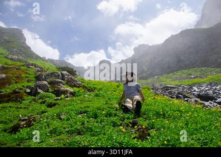 Mann, der auf einem Felsen auf einem Berg sitzt, in einer nebeligen Umgebung. Stockfoto