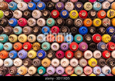Gebrauchte Graffiti-Spraydosen in einer farbenfrohen dekorativen Hintergrundwand Stockfoto
