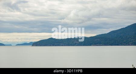 Malerischer Blick auf einen See und bewaldete Berge unter einem bewölkten Himmel Stockfoto