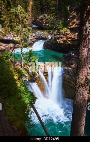 Der Wasserfall Fließt In Den Turquoise Pool Zwischen Wald Und Rocky Canyon Stockfoto
