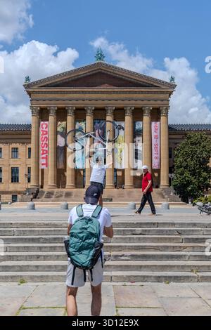 Ein Mann macht ein Foto von einem Philadelphia Museum of Art Er hält ein Fahrrad in der Hand Stockfoto