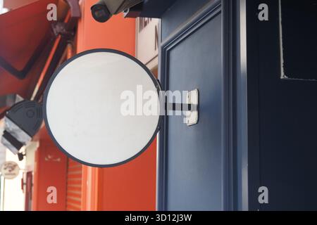 Rundes Schild an einer blauen Mauer in einer lebhaften Stadtkulisse Stockfoto