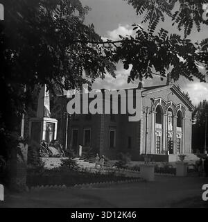 Der Kulturpalast der Eisenbahnarbeiter (DK ZHD) in Sloviansk, 1970er Jahre Dieses Archivfoto aus der UdSSR, der ukrainischen SSR, zeigt das beeindruckende Gebäude im neoklassizistischen stalinistischen Architekturstil. Daneben steht ein Denkmal aus dem Zweiten Weltkrieg mit einer Statue und Tafeln. Kulturpaläste waren zentrale Zentren für Kunst, Freizeit und Veranstaltungen in der Sowjetunion. Dieses Bild zeigt einen typischen sowjetischen öffentlichen Raum, der Kultur und historisches Gedächtnis verbindet. Ein wertvolles Dokument des friedlichen Bürgerlebens im Donbass vor dem Krieg. Stockfoto