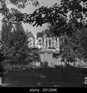 Ein Denkmal für Wladimir Lenin steht in einem grünen Park oder Platz in der Stadt Sloviansk, 1970er Jahre Dieses Archivfoto aus der UdSSR, der ukrainischen SSR, zeigt die ikonische Statue des kommunistischen Führers. Lenin ist in voller Länge auf einem hohen Sockel dargestellt, umgeben von Reifen Bäumen und Blumenbeeten. Solche Denkmäler waren allgegenwärtige Symbole der sowjetischen Ideologie in jeder Stadt. Dieses nostalgische Bild fängt einen typischen öffentlichen Raum während der Breschnew-Ära ein. Ein wertvolles historisches Dokument über das friedliche Leben im Donbass vor dem Krieg. Stockfoto