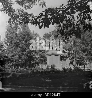 Ein Denkmal für Wladimir Lenin steht in einem grünen Park oder Platz in der Stadt Sloviansk, 1970er Jahre Dieses Archivfoto aus der UdSSR, der ukrainischen SSR, zeigt die ikonische Statue des kommunistischen Führers. Lenin ist in voller Länge auf einem hohen Sockel dargestellt, umgeben von Reifen Bäumen und Blumenbeeten. Solche Denkmäler waren allgegenwärtige Symbole der sowjetischen Ideologie in jeder Stadt. Dieses nostalgische Bild fängt einen typischen öffentlichen Raum während der Breschnew-Ära ein. Ein wertvolles historisches Dokument über das friedliche Leben im Donbass vor dem Krieg. Stockfoto