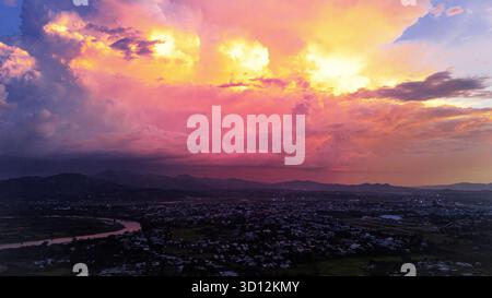 Dramatischer Sonnenuntergang über Kontum Stadtlandschaft mit lebhaften Wolken, Vietnam Stockfoto