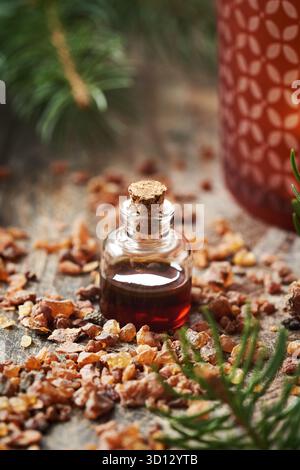 Ätherisches Myrrhenöl in einer Glasflasche mit Weihnachtsdekoration auf einem Tisch Stockfoto