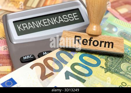 GKV-Reform im Display von einem Taschenrechner steht als Digitalanzeige das Wort Krankenkasse und eineÂ Holzstempel mit dem Aufdruck Reform als Symbol Stockfoto