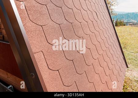 Asphaltschindeln, die ein modernes kleines Hausdach bedecken, zeigen neue Baudetails und architektonische Muster Stockfoto