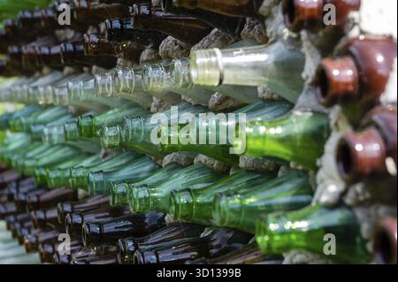 Weinflaschen in einer Reihe auf einer Steinmauer. Abstrakte dekorative Glasflasche mit Hintergrundmuster. Nahaufnahme Stockfoto
