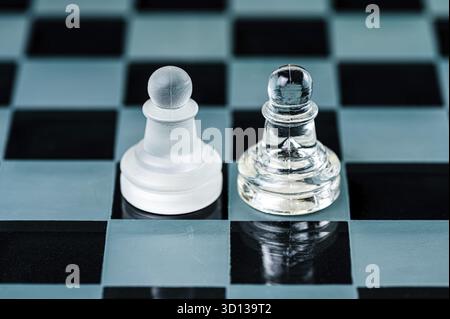 Zwei gegnerische Glasschachfiguren auf einem Glasschachbrett, schwarzer Hintergrund, Kopierraum Stockfoto