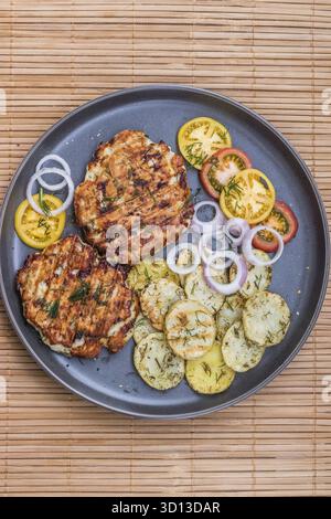 Gehacktes Hähnchenkotelett mit gegrilltem Gemüse liegt auf einem Teller. Gegrilltes Geflügel und Gemüse. Wunderschönes Essen. Speiseplan. Braten Stockfoto