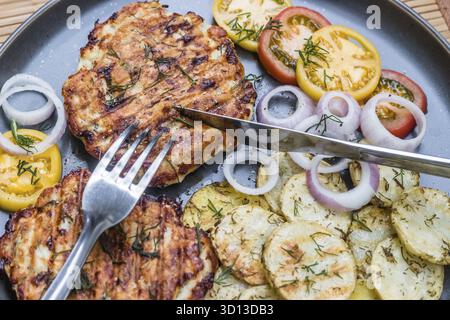 Gehacktes Hähnchenkotelett mit gegrilltem Gemüse liegt auf einem Teller. Gegrilltes Geflügel und Gemüse. Wunderschönes Essen. Speiseplan. Braten Stockfoto