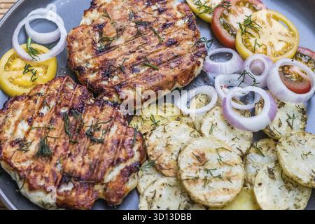 Gehacktes Hähnchenkotelett mit gegrilltem Gemüse liegt auf einem Teller. Gegrilltes Geflügel und Gemüse. Wunderschönes Essen. Speiseplan. Braten Stockfoto