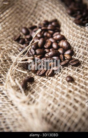 Geröstete Kaffeebohnen auf Sackleinen bestreuen Stockfoto