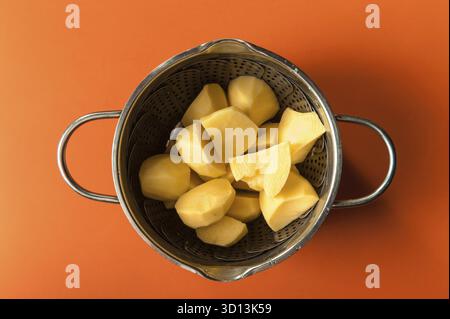 Rohe Kartoffeln in Scheiben in einer Pfanne auf rotem Hintergrund Stockfoto