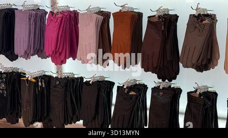 Handschuhe in verschiedenen Farben und Stilen auf Kleiderbügeln im Ladenlokal. Mobiles Foto Stockfoto