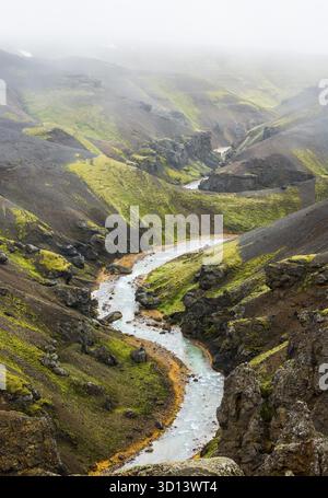 Fluss mit roten Ufern und schwarz-roten Lava schneebedeckten Bergen in Kerlingarfjoll auf Island, IJsland Stockfoto