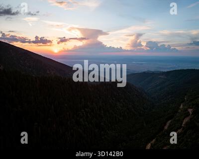 Sonnenuntergang über kurvenreiche Straße durch das Bergwaldtal, Blick auf die Drohne aus der Luft Stockfoto