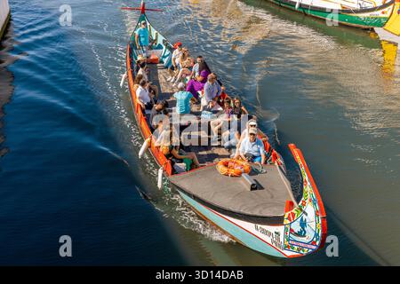 AVEIRO-Portugal: 13. Oktober 2025: Ein traditionelles, hoch dekoriertes Moliceiro-Boot, das aus der Sicht über der Höhe betrachtet wird, transportiert eine Gruppe von verschiedenen Stockfoto