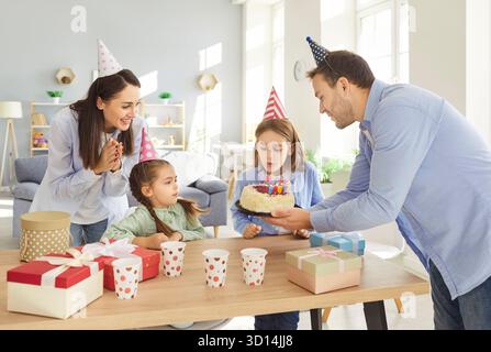Glückliche Familie feiert Kindergeburtstag, Sohn wünscht sich und bläst Kerzen in festlicher Atmosphäre. Stockfoto