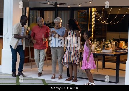 Draußen feiern, generationenübergreifende Familiengespräche führen und gemeinsam Drinks trinken. Feiern, Treffen, Bonding, Freizeit, Getränke, Unterhaltung || Modell veröffentlicht Stockfoto
