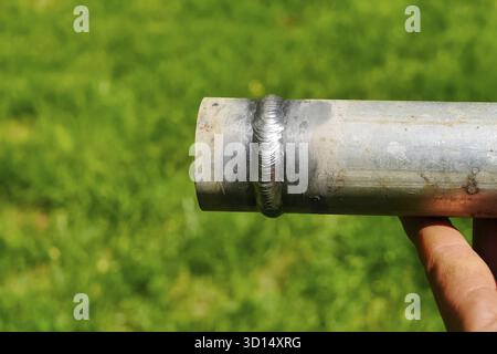 Metallrohr mit einer Schweißnaht in der Hand des Menschen des Schweißers Stockfoto