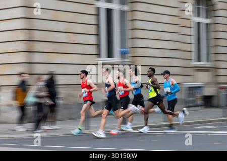 26. Oktober 2025, Hessen, Frankfurt/Main: Leichtathletik: Marathon. Läufer laufen an stehenden Passanten vorbei. Der Frankfurter Marathon ist der älteste Stadtmarathon Deutschlands. Foto: Hannes P. Albert/dpa Stockfoto