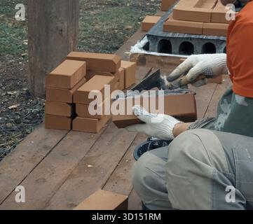 Ein Mann baut eine Mauer. Brick hat die Lösung aufgesetzt. Bau eines Backsteinhauses Stockfoto
