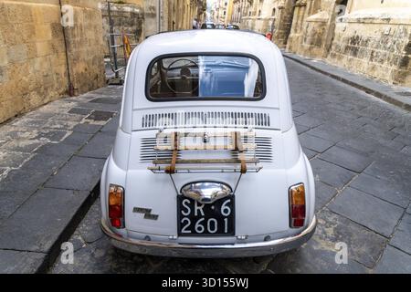 Noto, Sizilien - Italien - 04-06-2025: Rückansicht eines alten weißen Fiat 500, der auf einer schmalen Kopfsteinpflasterstraße in Noto geparkt ist, mit Gepäckablage und Stockfoto