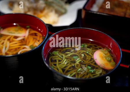 Zwei Schüsseln dampfender japanischer Soba-Nudeln in pikanter Brühe, garniert mit grünen Zwiebeln und Fischkuchenscheiben. Ein warmer und authentischer Geschmack von Tradition Stockfoto