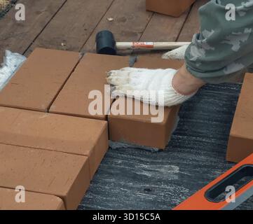 Ein Mann baut eine Mauer. Brick hat die Lösung aufgesetzt. Bau eines Backsteinhauses Stockfoto