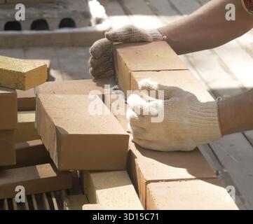 Ein Mann baut eine Mauer. Brick hat die Lösung aufgesetzt. Bau eines Backsteinhauses Stockfoto