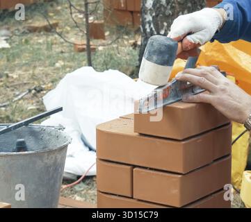 Ein Mann baut eine Mauer. Brick hat die Lösung aufgesetzt. Bau eines Backsteinhauses Stockfoto