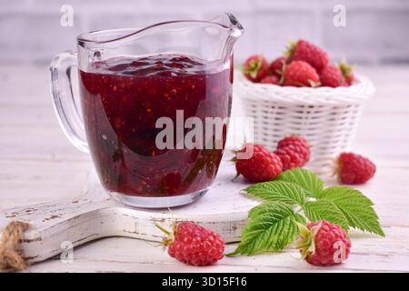Himbeermarmelade in einem Glas-Saucboot auf weißem Holzhintergrund. Stockfoto