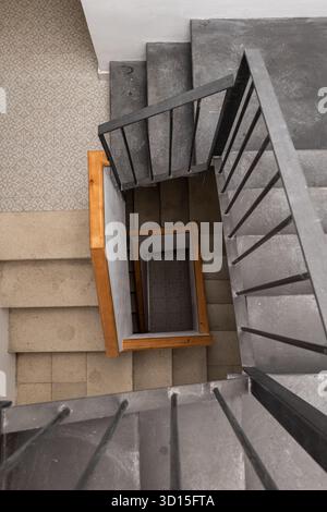 Eine moderne Wendeltreppe mit Holz- und Betonelementen. Die Ansicht ist von oben und zeigt das einzigartige Design und die Materialien, die im verwendet werden Stockfoto