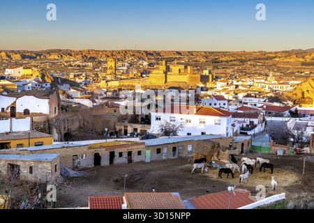 Guadix, Granada - Spanien - 24.01.2024: Ein Blick auf Guadix zeigt typische Höhlenhäuser und die Alcazaba in der Ferne, beleuchtet von der Abendbeleuchtung Stockfoto