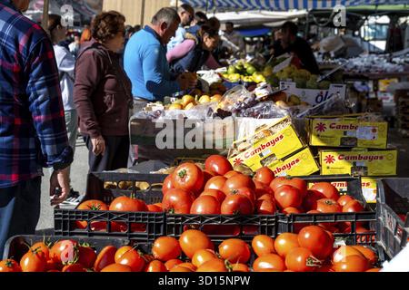 Guadix, Granada - Spanien - 24.01.2024: Frische Kisten mit Tomaten, Äpfeln und Birnen an einem Marktstand im Freien mit Besuchern im Hintergrund Stockfoto