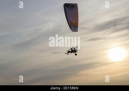 Motorisiertes Gleitschirmfliegen vor dem Hintergrund der untergehenden Sonne Stockfoto