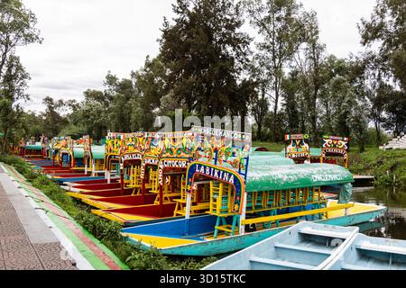 Bemalte Trajineras Reihen sich im Cuemanco-Kanal, Xochimilco, Teil des UNESCO-Weltkulturerbes von Mexiko City. Stockfoto